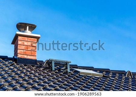 New black tiled roof with chimney. New roof of a detached house with chimney against the sky. Exterior building design. Roof tiles close up