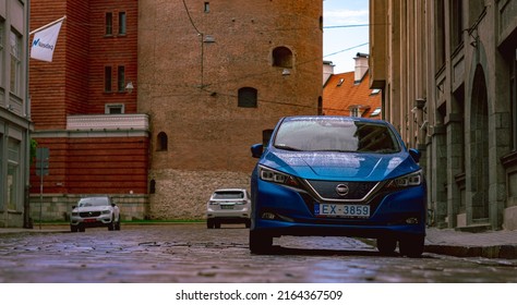 New Blue Nissan Electric Car In The Center Of Old Town After Rain. Riga, Latvia, 05.28.2022