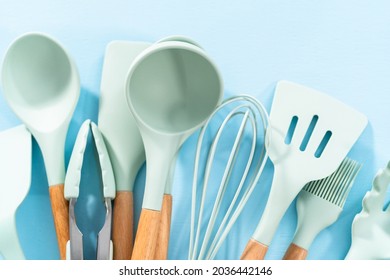 New Blue Silicone Kitchen Utensils With Wooden Handles On A Blue Background.