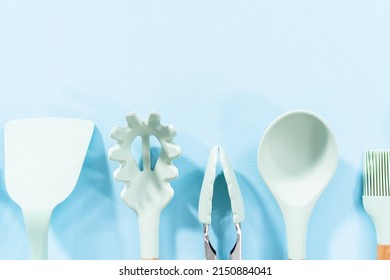 New Blue Silicone Kitchen Utensils With Wooden Handles On A Blue Background.