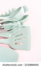 New Blue Silicone Kitchen Utensils With Wooden Handles On A Pink Background.