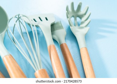 New Blue Silicone Kitchen Utensils With Wooden Handles On A Blue Background.