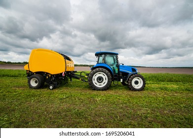 New Blue Tractor With Baler In Motion In Farm Work At Field With Green Grass