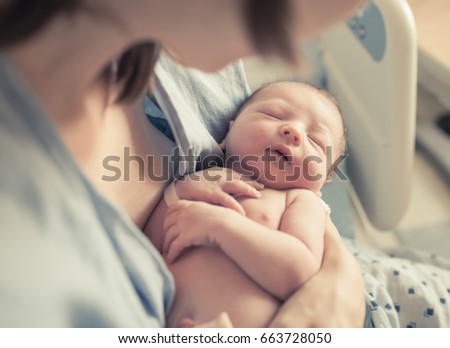 New born baby boy resting in mothers arms. 