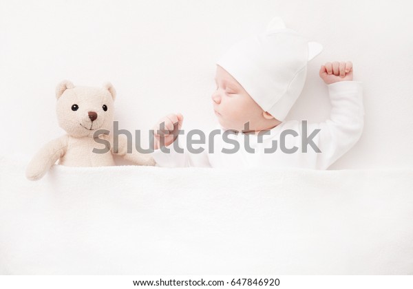 New born Baby\
girl sleeping with her teddy\
bear