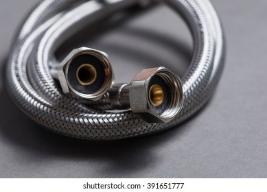 New braided stainless steel water hose over grey background