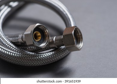 New braided stainless steel water hose over grey background