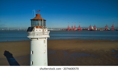 New Brighton, Wirral, Merseyside, England, Britain, November 2021, Aerial view of New Brighton (Perch Rock) lighthouse with giant red cranes at Port of Liverpool in background