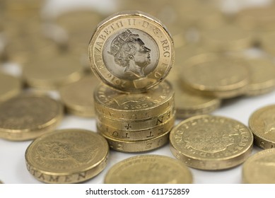 New British one pound sterling coin alongside the old one pound coins up close macro studio shot against a shiny reflective White background