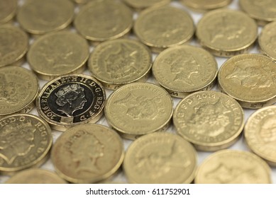 New British one pound sterling coin alongside the old one pound coins up close macro studio shot against a shiny reflective White background