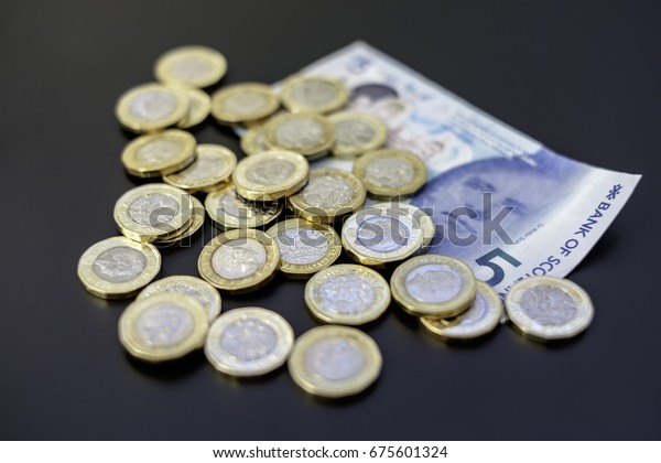 New british one sterling pound coins on dark
background with a 5 pounds
note.