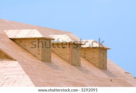 New building under construction showing plywood roof sheeting and three dormers