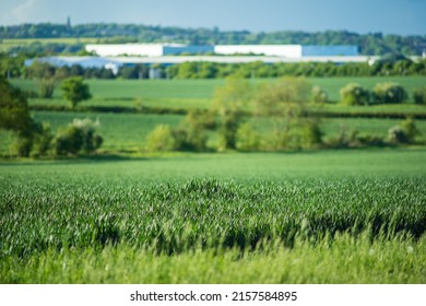 New Built Distribution Warehouse Building With Farm Fields In Foreground In England Uk