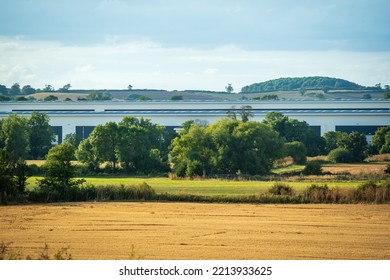 New Built Distribution Warehouse Building With Farm Fields In Foreground In England Uk