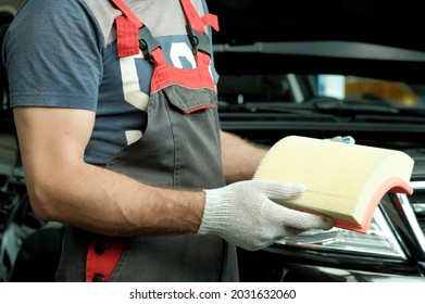 A New Car Air Filter In The Hands Of An Auto Mechanic. Inspection Of The Spare Part Before Replacing The Overhead Line During The Repair And Maintenance Of The Car At The Car Service Station.