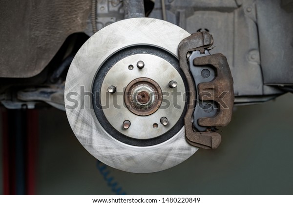 New car brake disc\
without wheels. Suspension of car in car service. Close up.Brake\
discs installed at car.