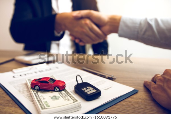 New car buyers and car salesmen are\
shaking hands to make agreements about car\
sales.
