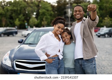 New Car. Happy Black Family Showing Own Automobile Key To Camera Standing Near Auto Posing Outdoor. Vehicle Purchase And Rent, Dealership Advertisement Concept