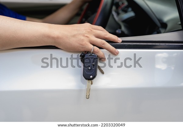The new car owner put the key on his finger and put\
it on the car door.