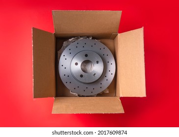 New Car Parts. Box With A New Ventilated Brake Discs On A Red Background. Overhead View.