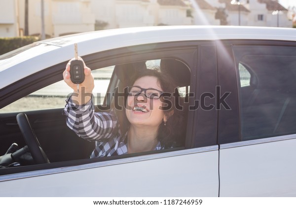 New car, purchase and driver\
concept - Attractive happy woman shows keys from the new\
car