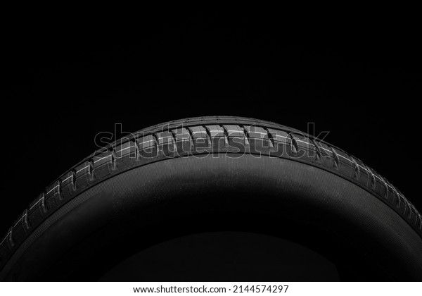 New car\
tire. Road wheel on dark background. Summer Tire with asymmetric\
tread design. Driving car concept.\
