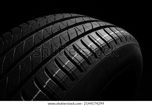 New car\
tire. Road wheel on dark background. Summer Tire with asymmetric\
tread design. Driving car concept.\
