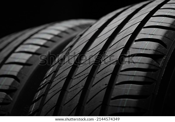 New car tires. Group of road wheels on dark\
background. Summer Tires with asymmetric tread design. Driving car\
concept. Close-up