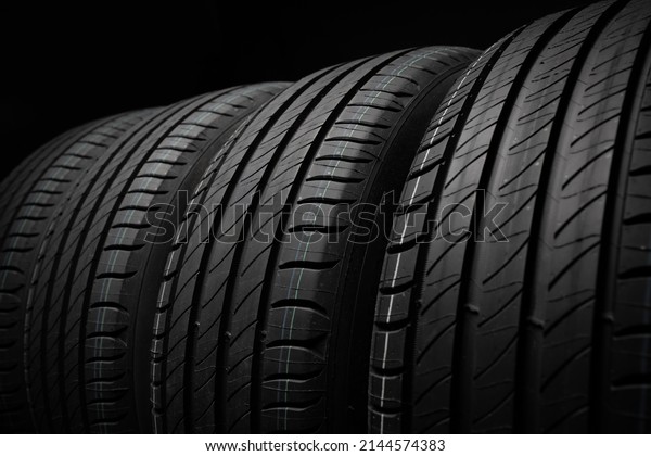 New car tires. Group of road wheels on dark\
background. Summer Tires with asymmetric tread design. Driving car\
concept. Close-up