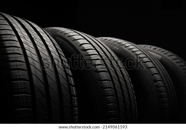 New\
car tires. Group of road wheels on dark background. Summer Tires\
with asymmetric tread design. Driving car\
concept.
