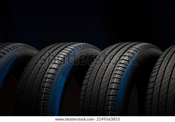 New\
car tires. Group of road wheels on dark background. Summer Tires\
with asymmetric tread design. Driving car\
concept.