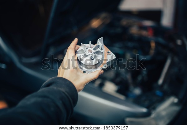 new car water\
pump in hand of auto\
mechanic
