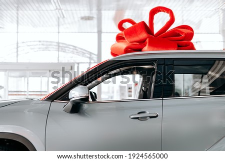 The new car is wrapped in a red bow. Beautiful gift concept 