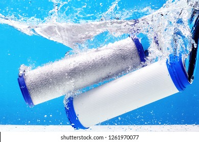 New carbon filter cartridge for house water filtration system isolated on blue background. Splash. Concept.
