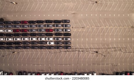 New Cars Located At The Factory Parking Lot Aerial View At Golden Hour. Car Manufactory Parking Area For A New Hybrid EV. High Tech Green Electric Vehicles Sorted After Industrial Production Conveyor.