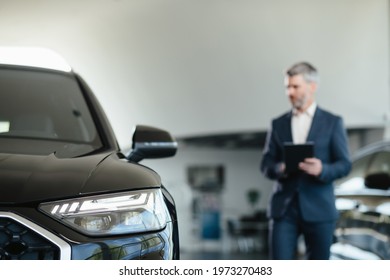 New Cars In Showroom. Dealership Concept, Focus On Car On Background Car Dealer Using Digital Tablet. Sales Agent Working
