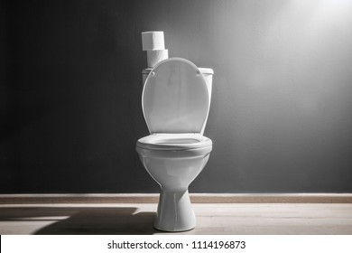 New ceramic toilet bowl near grey wall, side light