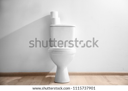 New ceramic toilet bowl near light wall