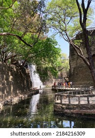 New Chandigarh, India – April 4, 2022: Beautiful Garden Path Along The Pond With Waterfall Feature At The Rock Garden Of Chandigarh, A Sculpture Garden For Rock Enthusiasts