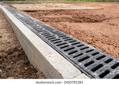 A new channel drain being laid against edging stone at the end of a residential driveway
