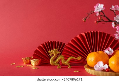 New Year’s charm: side view feng shui items, gold dragon, tangerines, sakura blossoms, and fans arranged on a table against a bold red background. Ideal for adding text or promotional content