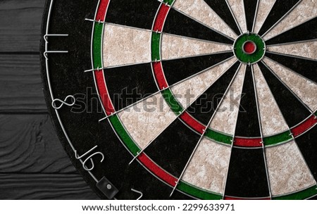 New classic professional sisal dart board on black wooden background. Close up