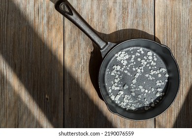 New Clean Cast Iron Pan With Salt On A Wooden Table. Background With Cooking Utensils And Kitchen Utensils For Frying. Caring For Cast Iron Cookware