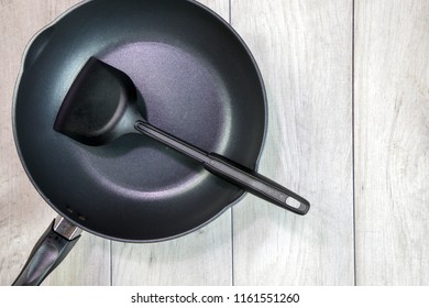 New Clean Empty Cast Iron Frying Pan And Spatula Overhead View On The Wood Background