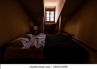 New Clean European Double Queen Bed With Slanted Ceiling And Window In Loft With Table And Pillows In Dark Bedroom Home Apartment Room