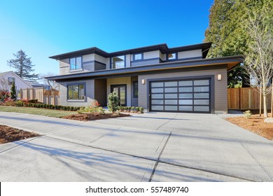 New Construction Home Exterior With Contemporary House Plan  Features Low Slope Roof, Brown Siding And Glass Garage Door. Northwest, USA