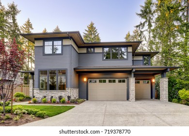 New construction home exterior with contemporary house plan  features gray wood siding, stone columns and two garage spaces. Northwest, USA - Shutterstock ID 719378770