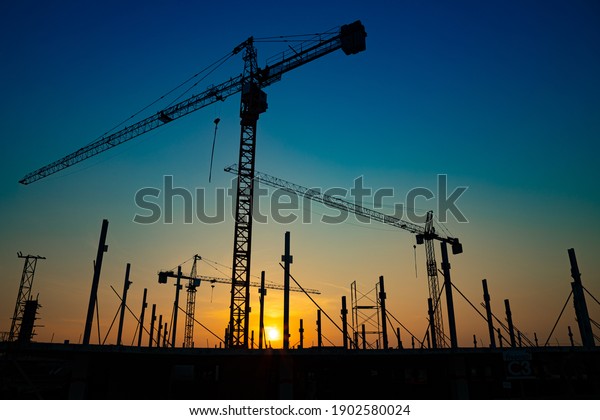 New construction site with cranes on orange\
sunset, sunrise sky background. Steel frame structure, structural\
steel beam build large buildings at construction site .\
construction machinery.