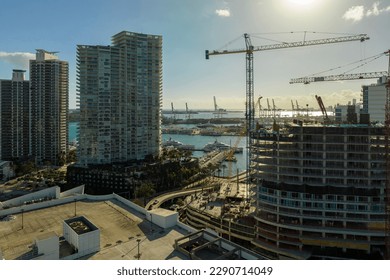 New construction site of developing residense in american urban area. Industrial tower lifting cranes in Miami, Florida. Concept of housing growth in the USA