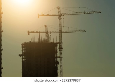 New construction site of developing residense in american urban area at sunset. Industrial tower lifting cranes in Miami, Florida. Concept of housing growth in the USA